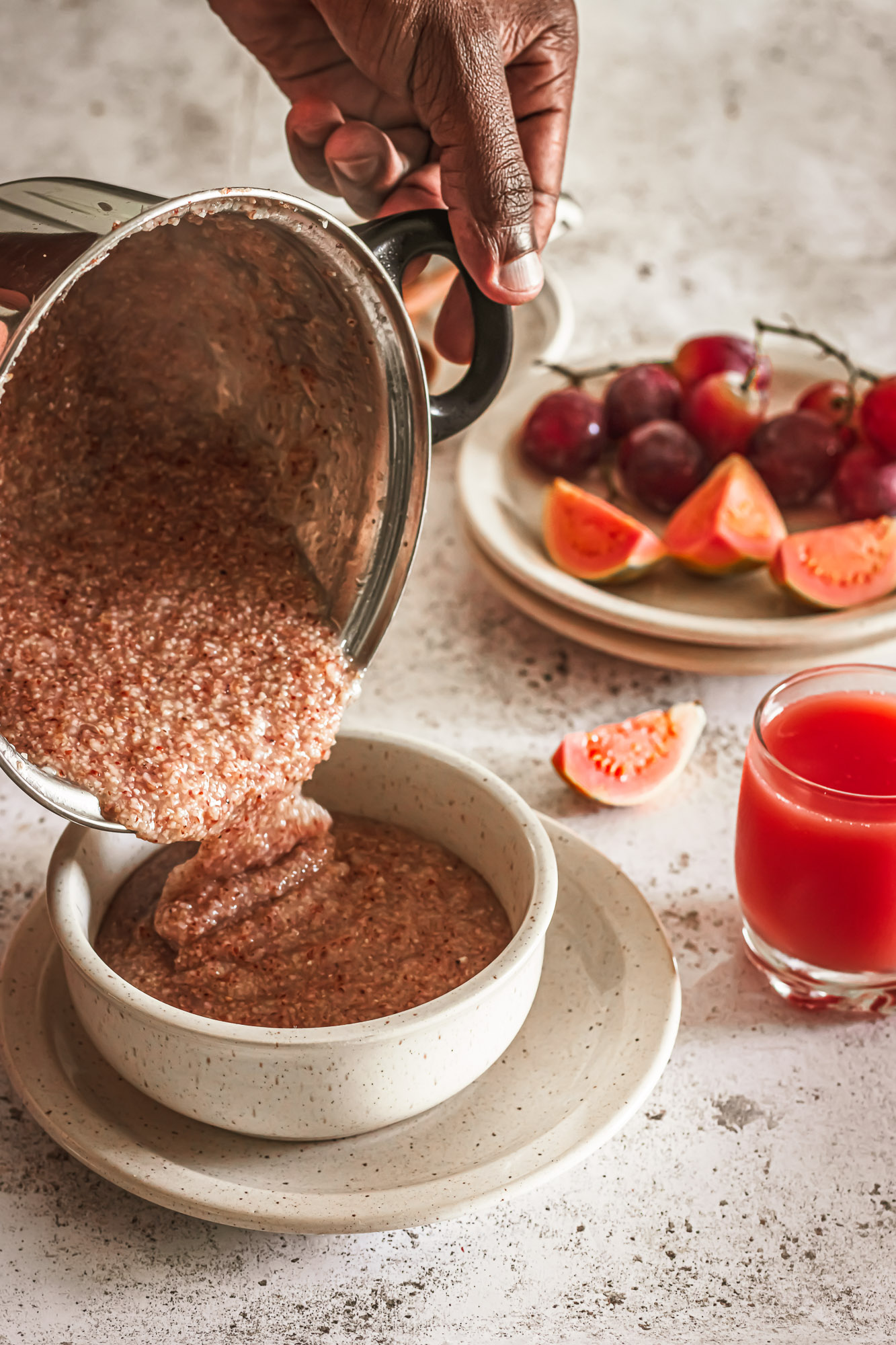 Pouring hot sorghum porridge from a saucepan into a breakfast bowl