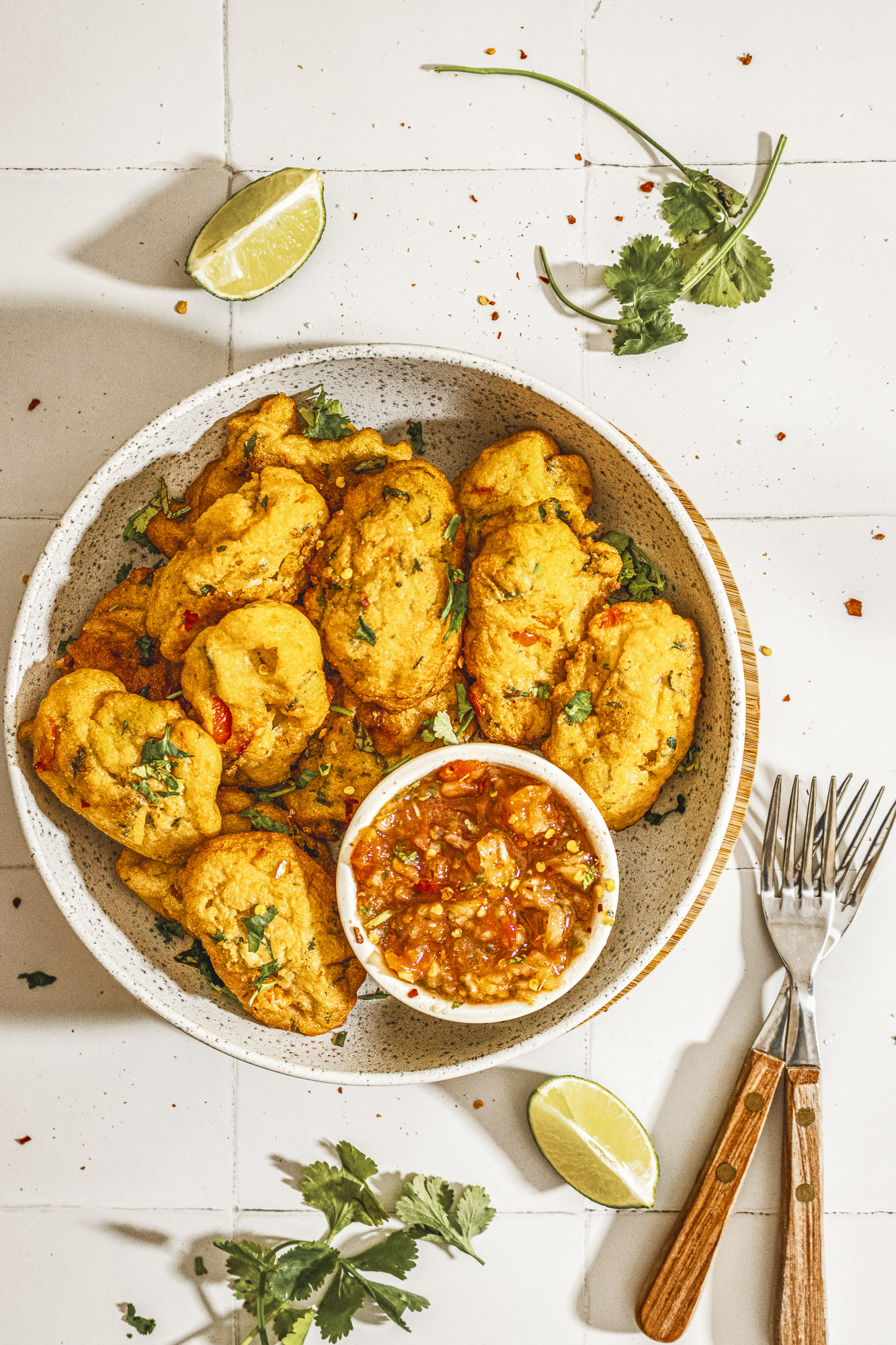 Flat lay of golden Nigerian akara bean fritters served with spicy tomato salsa and garnished with coriander leaves.