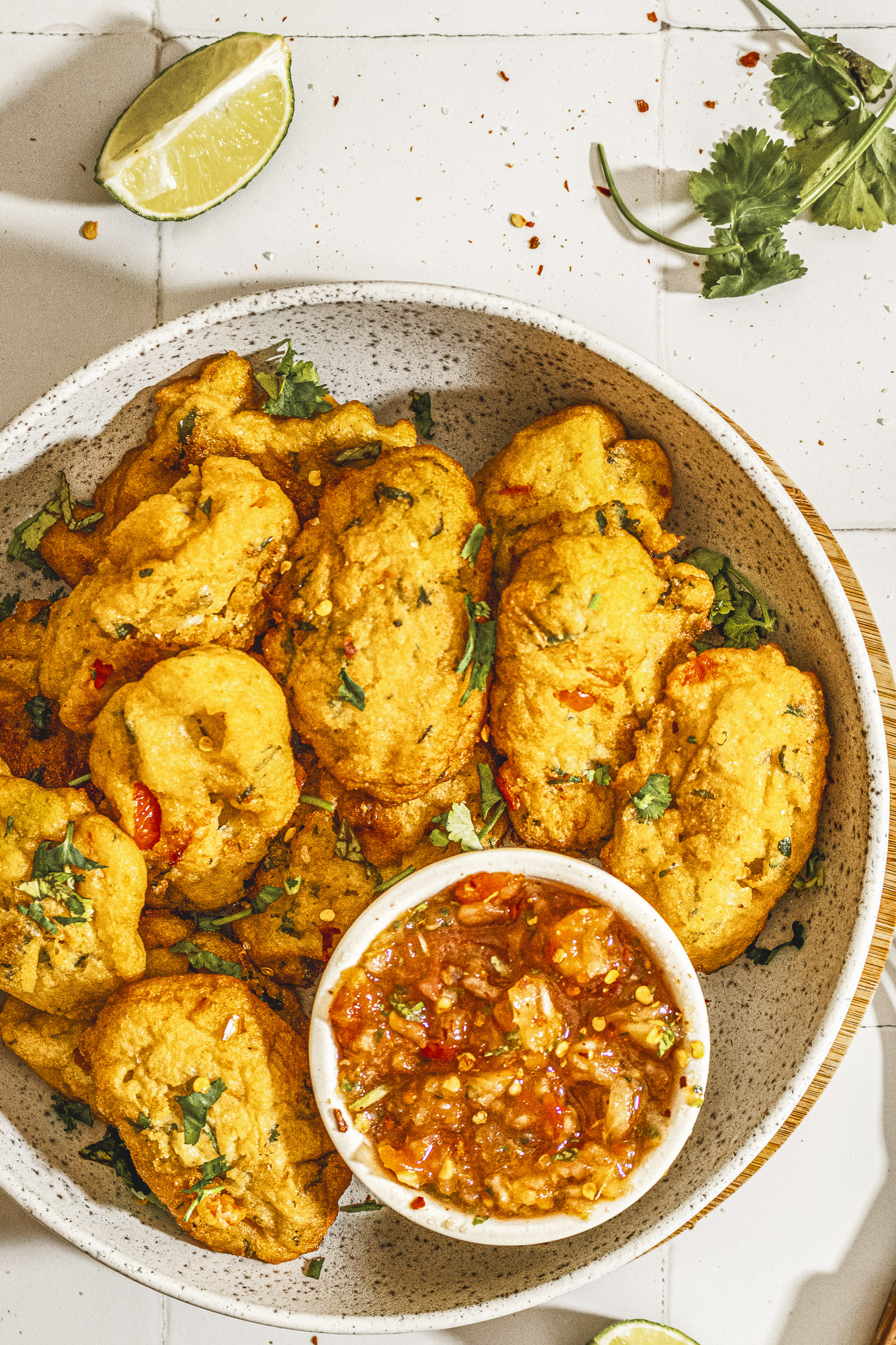 A bright overhead shot of Nigerian akara &mdash; golden, fluffy black-eyed pea fritters &mdash; arranged beside fresh salsa and scattered coriander. A modern take on classic African food that&rsquo;s perfect for breakfast or as a Nigerian akara snack.