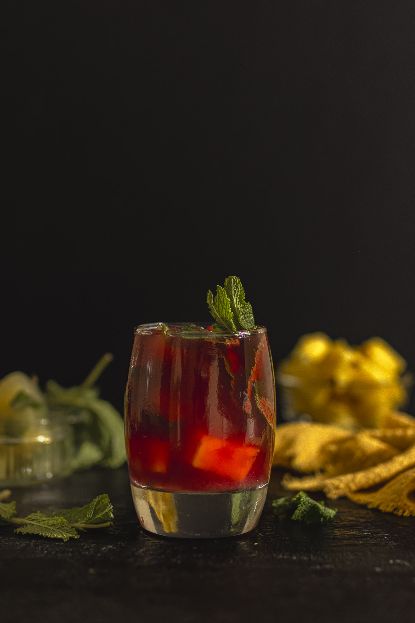 A vibrant hibiscus tea mocktail served over ice and styled with pineapple chunks, mint leaves, and &mdash; a refreshing non-alcoholic hibiscus drink with ruby-red colour and tropical aroma.